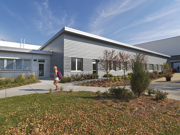 Different metal cladding distinguishes the office and shop areas at the Joliet Junior College Facility Services Building. The less visible garage areas (upper left) are built with utilitarian precast concrete painted white to match other campus structures.