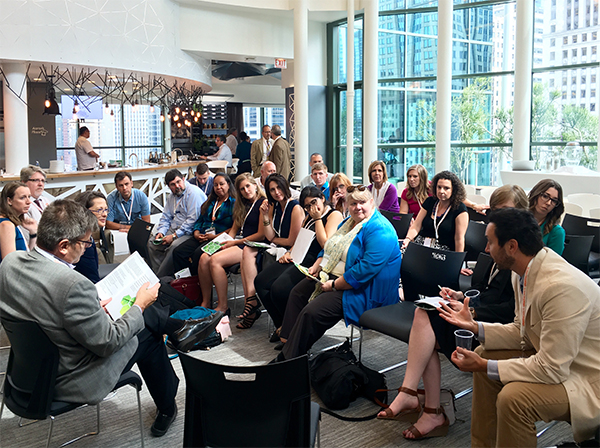 Following his presentation, Tommy Zakrzewski (right) discusses the relationship between biophilic design and workplace productivity with a group of participants.