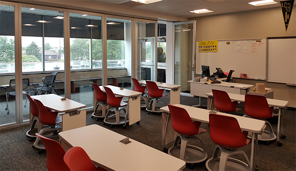 An AVID classroom supports MHS’s college prep programs. Glass partitions open to a break-out area in the background.