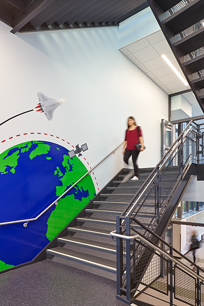 Staircases within the addition feature engaging wall graphics and views of the campus.