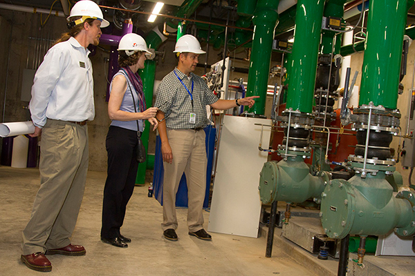 CLC and Cotter Consulting representatives examine the piping and heat pumps from the geothermal system, which has wells beneath the café.