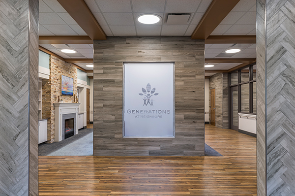 A frosted glass sign with the Generations Healthcare Network logo welcomes visitors. Wall and floor tile in different wood tones, along with a veneer stone fireplace, create a cozy feel.