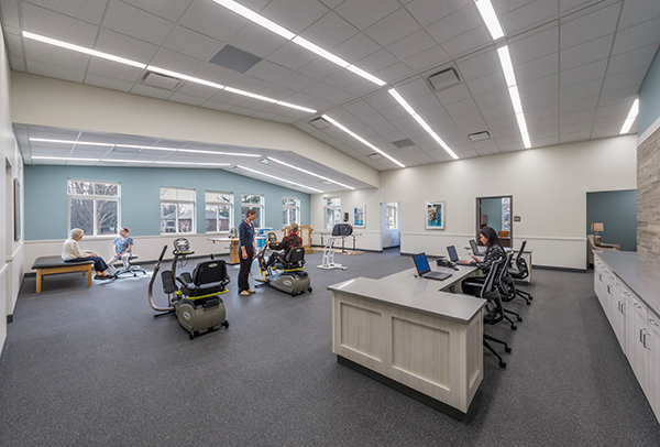 The new physical therapy space features new equipment, a staff desk, and a high vaulted ceiling.