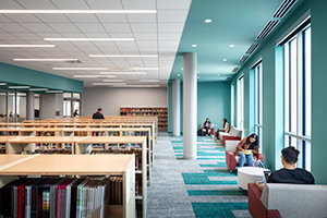 High school library with shelves and students working along window wall