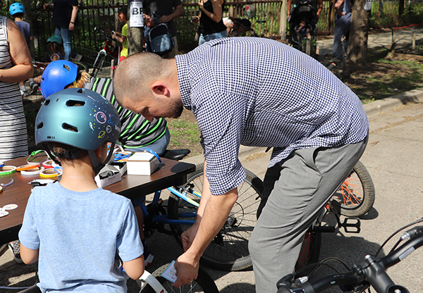 adult helps student affix sticker to bicycle