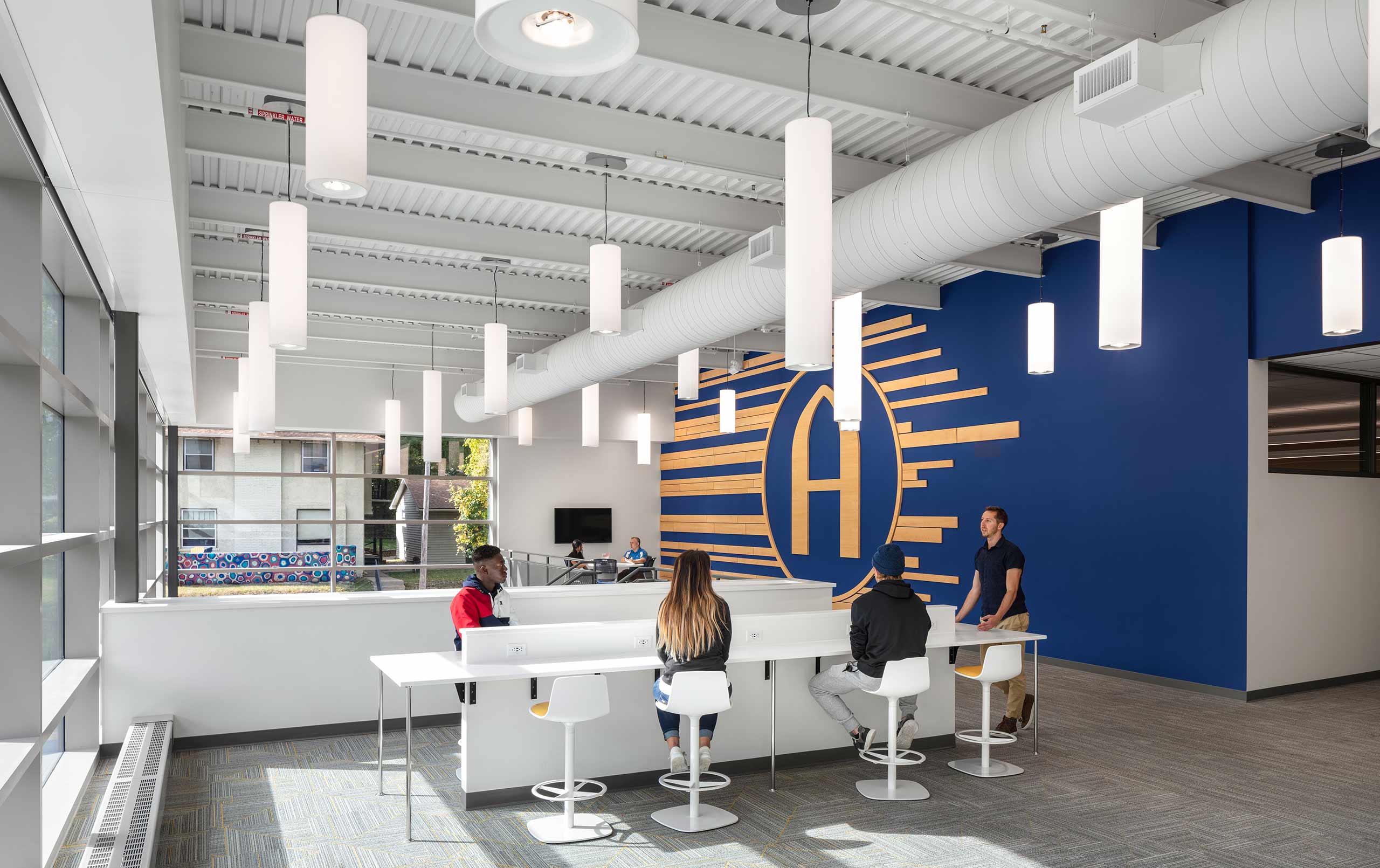 Students and staff in second-floor gathering area at Augusta College's Lindberg Center. Large Augustana "A" on the wall.