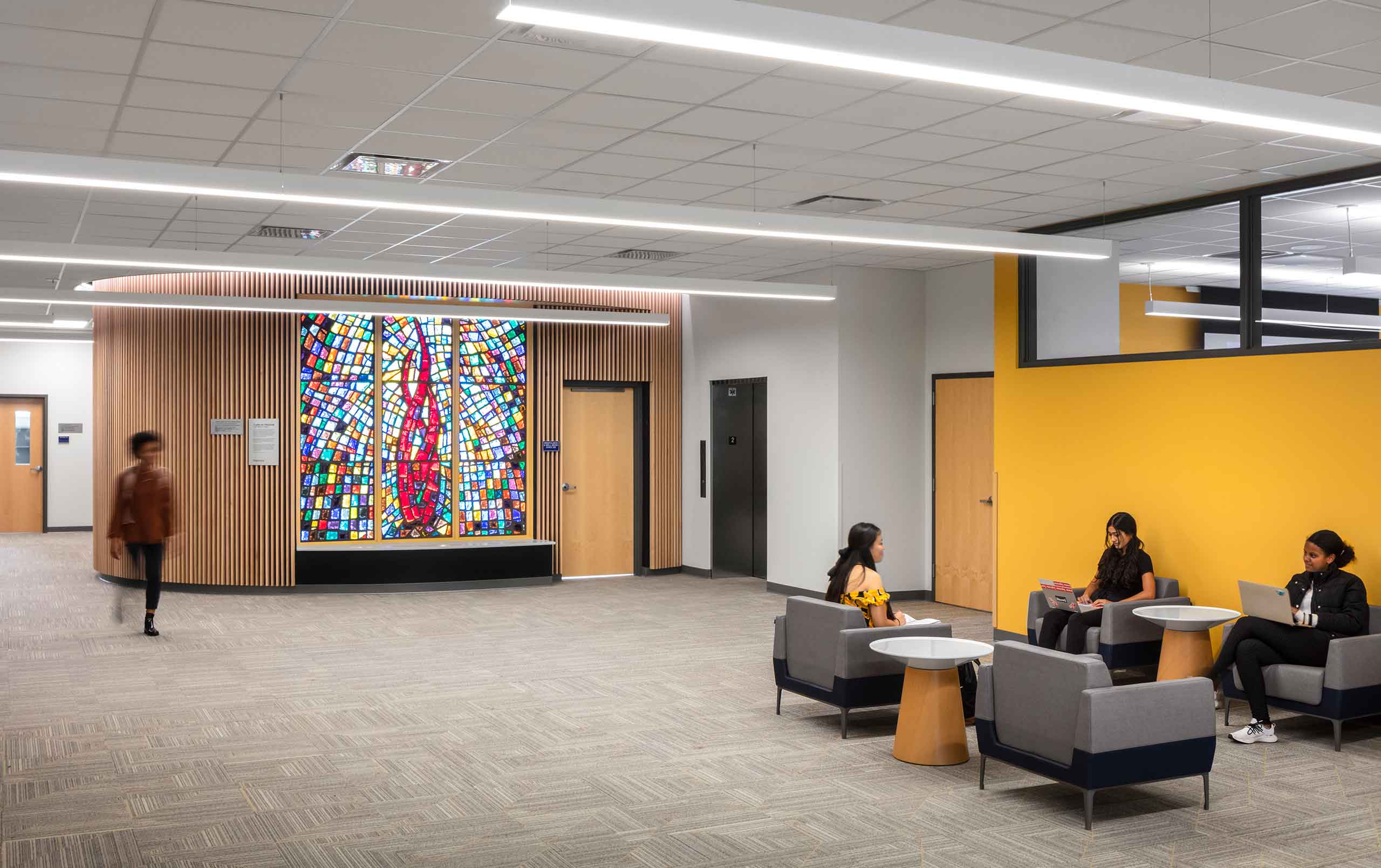 Students in second-floor corridor of Augustana College's Lindberg Center. Background shows stained glass window and meditation room.