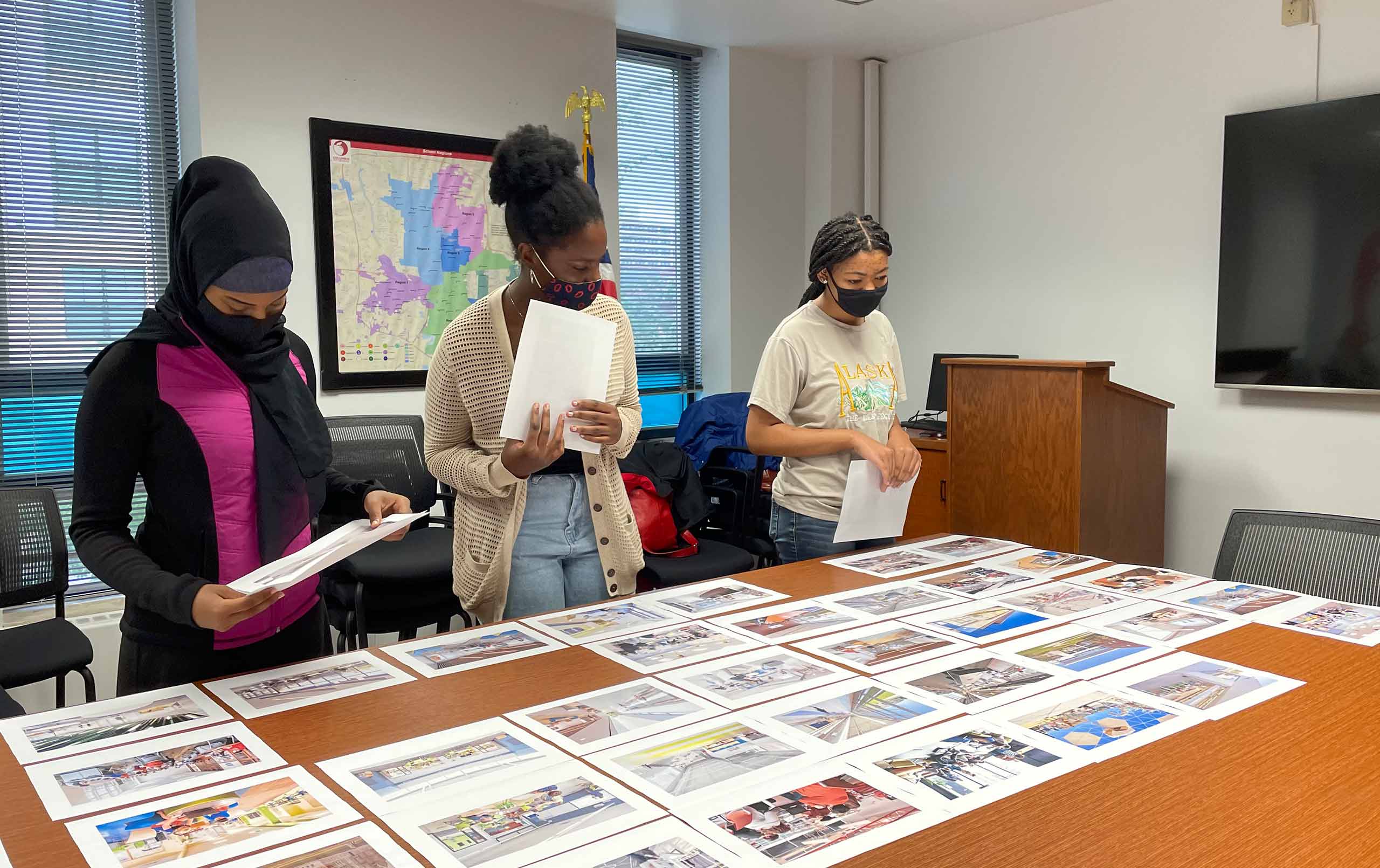 Three students collaborating on Columbus District Master Plan wot images on a table. 