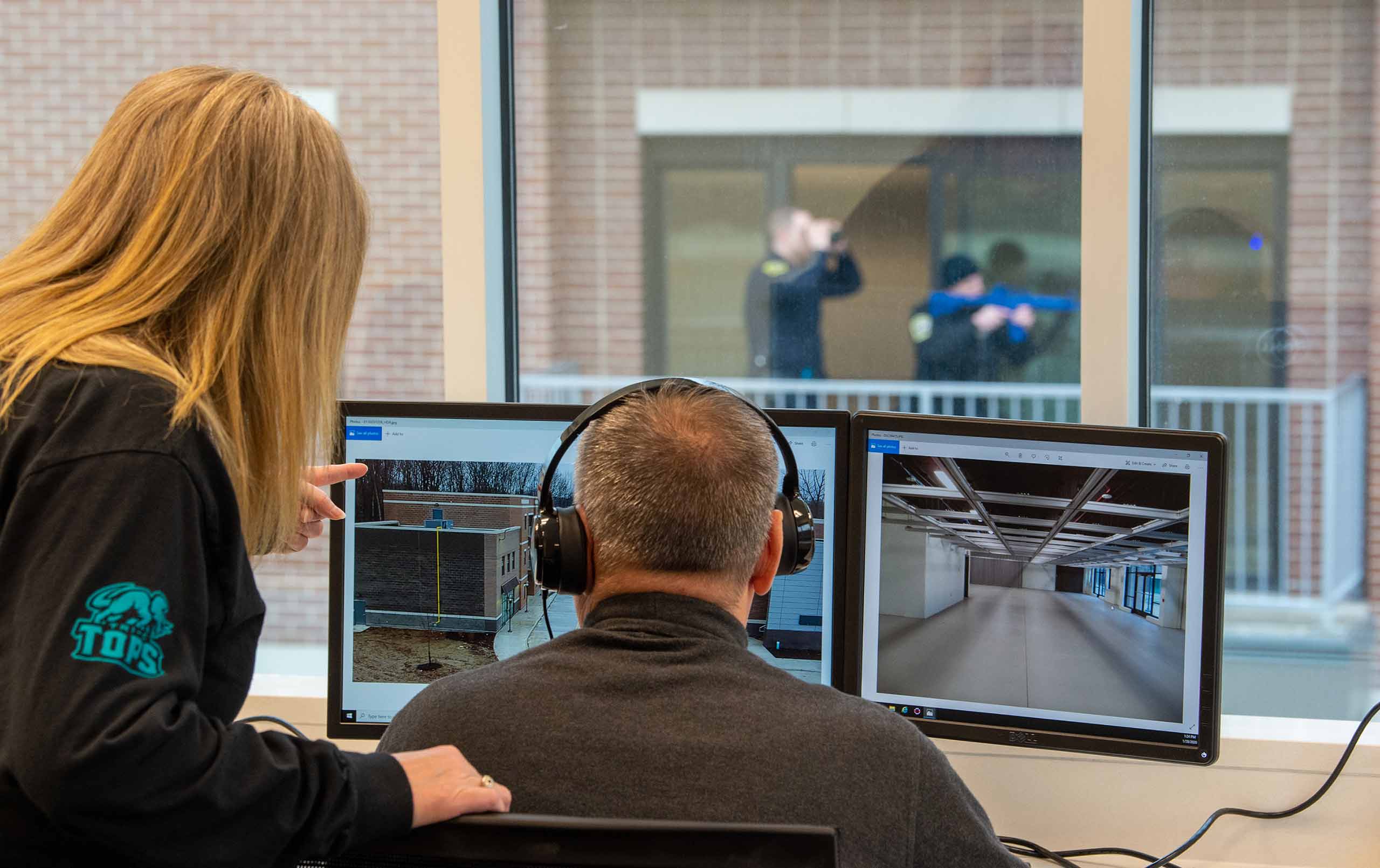 Two professionals monitoring officers in training at Cuyahoga Community College Simulated Scenario Village. 