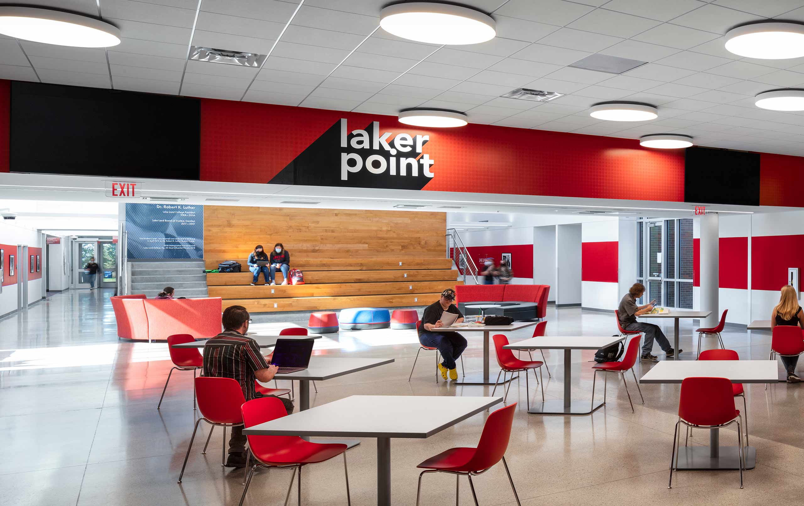 College cafeteria with red furnishings and wood feature wall in background