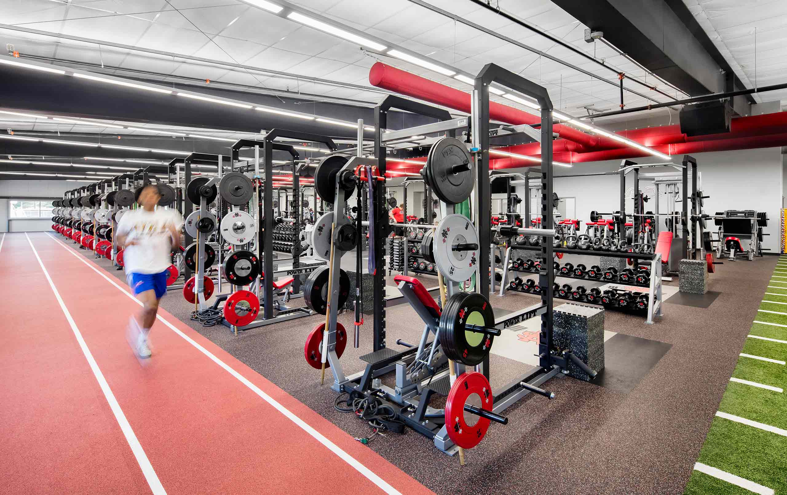 Student running around track field wrapped around North Scott High School athletic building's weight room. 