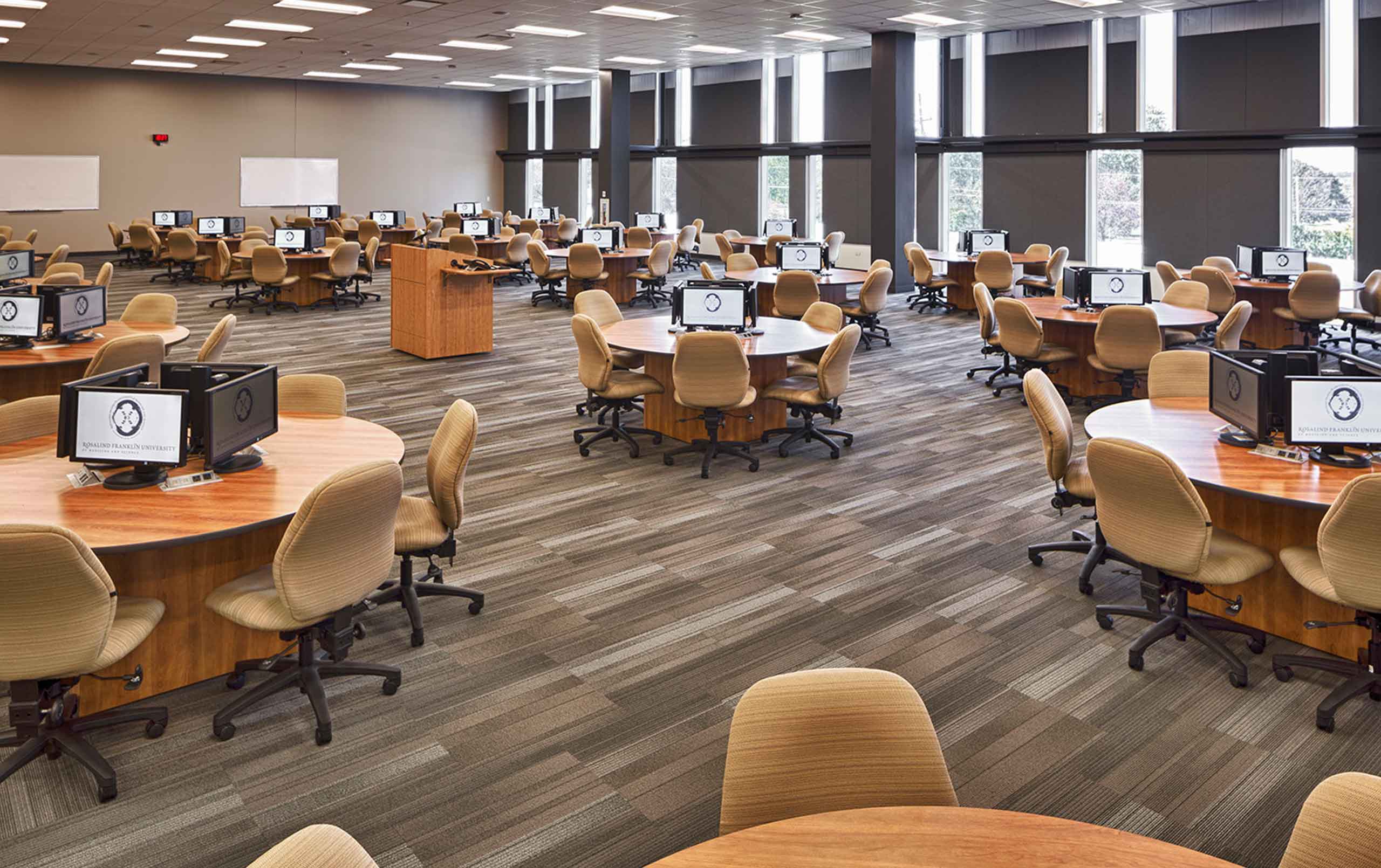 Interior of Rosalind Franklin University Centennial Center - large room with circular desks and computers. 