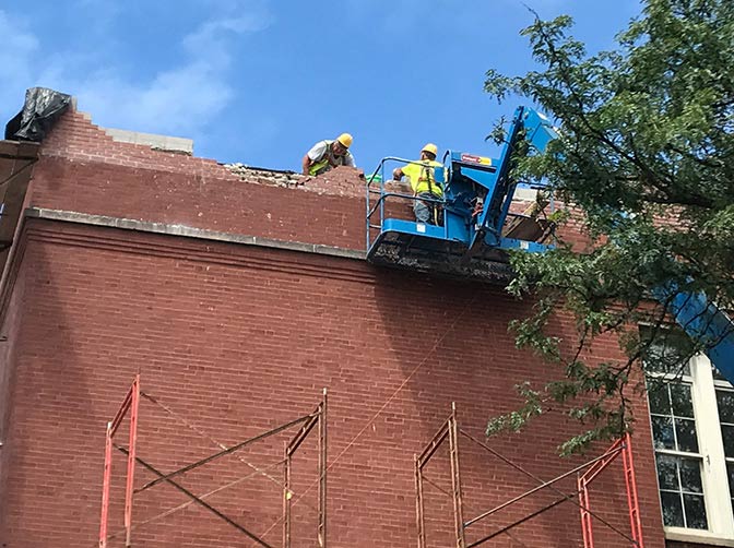 building construction site with workers restoring old brick facade