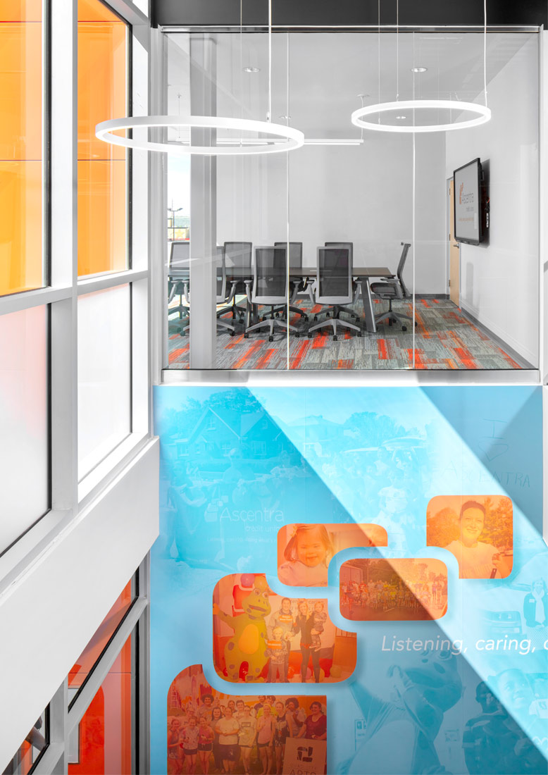 stairwell with view of upper-level conference room and wall graphic