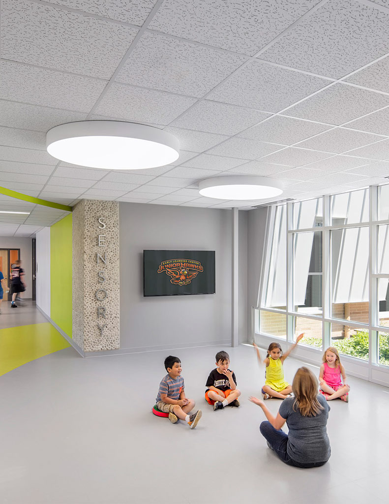 Early learning students in corridor with window displaying garden