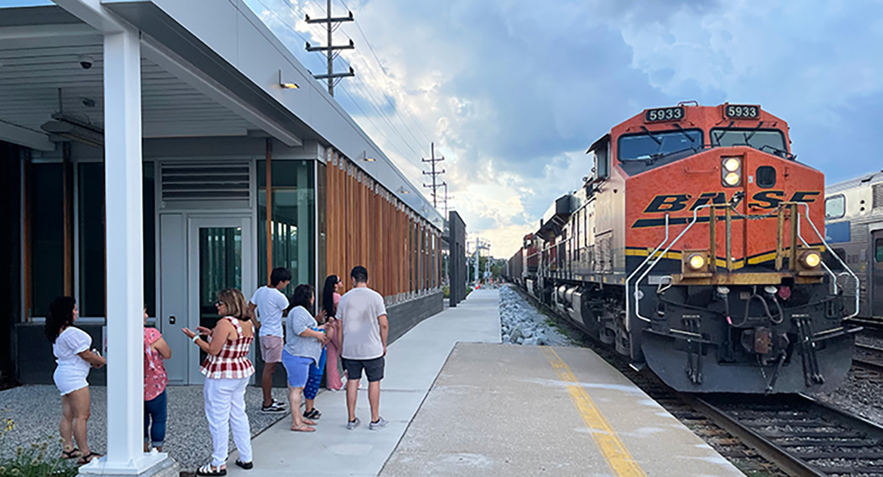 Commuters standing next to a contemporary train station while train approaches