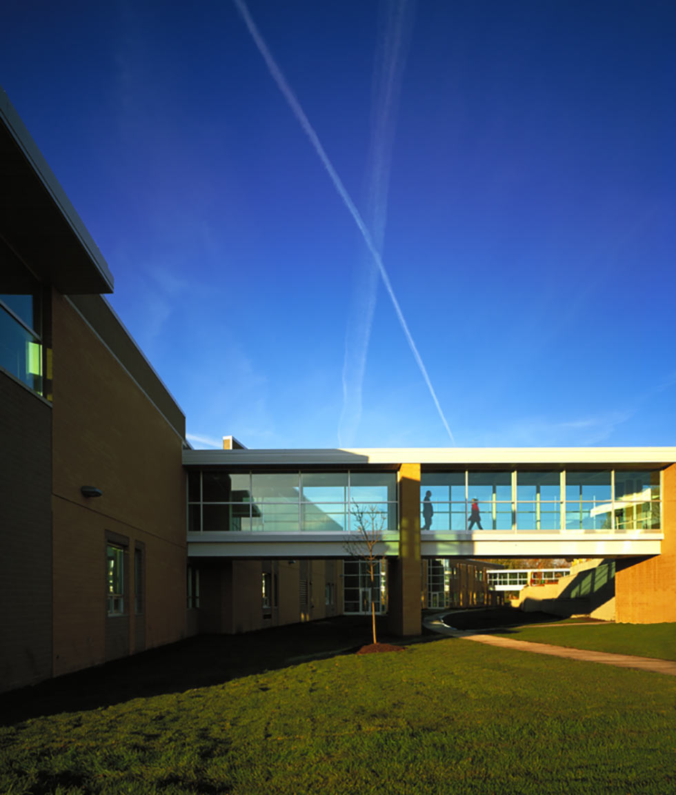 People walking through junior high school glass bridge spanning a courtyard