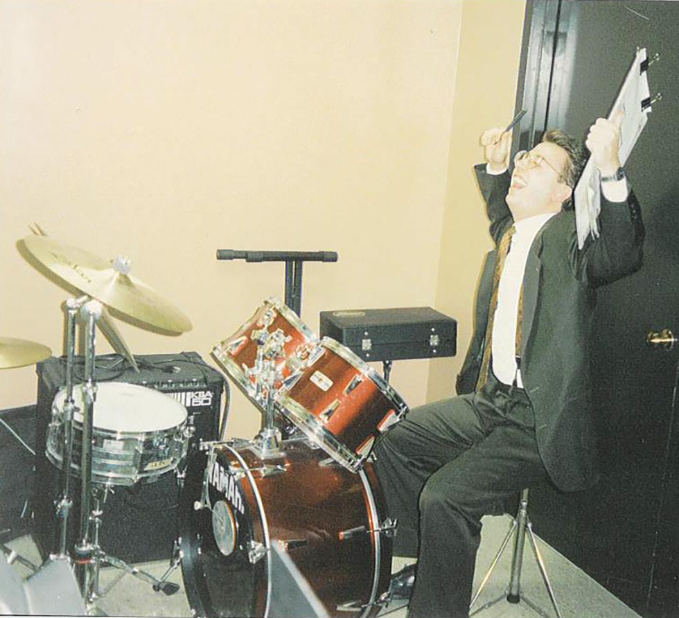 Architect in suit holding clipboard and playing drums