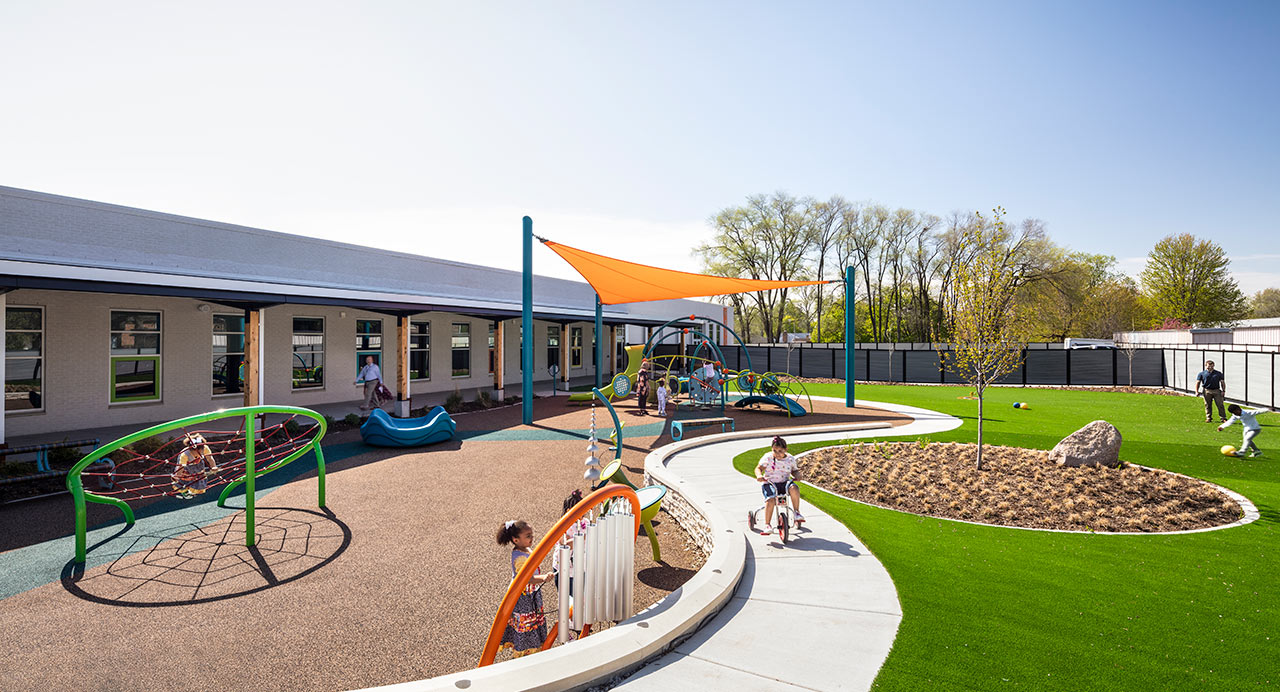 early learning outdoor space with playground and large grass area