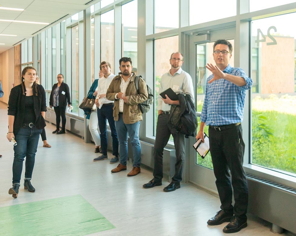 Architect leading tour of school with glass wall in background