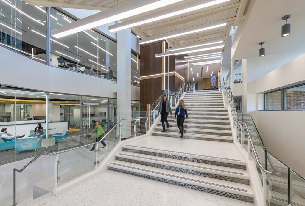 College atrium grand stair with glass wall displaying two-story library