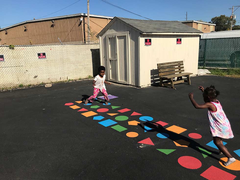 Girls playing game with colorful shapes on concrete