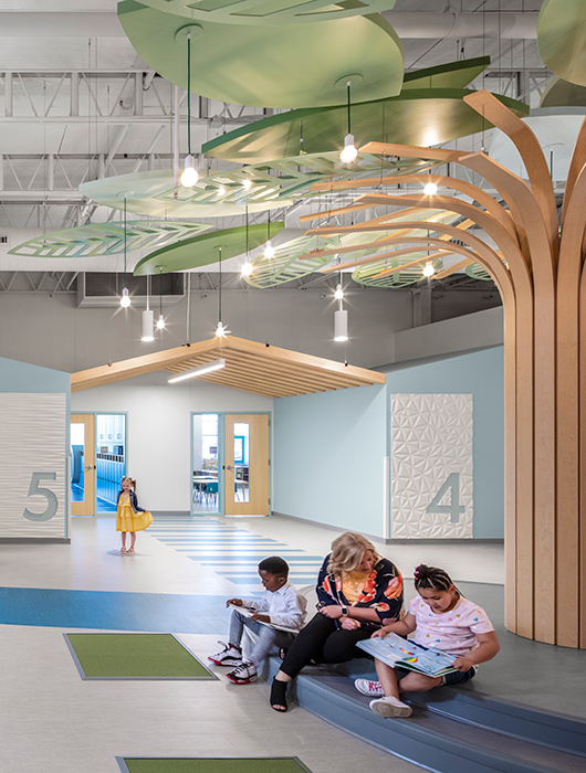 Teacher sits with students under abstracted tree in school corridor