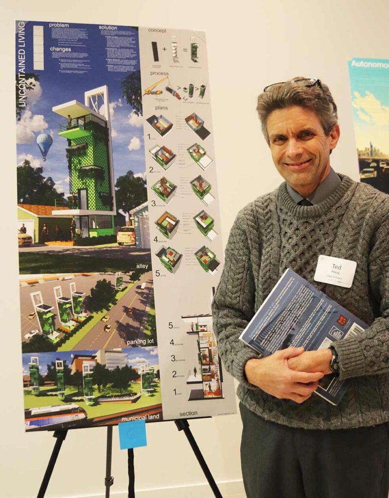 Ted Haug standing next to board with renderings of contemporary building