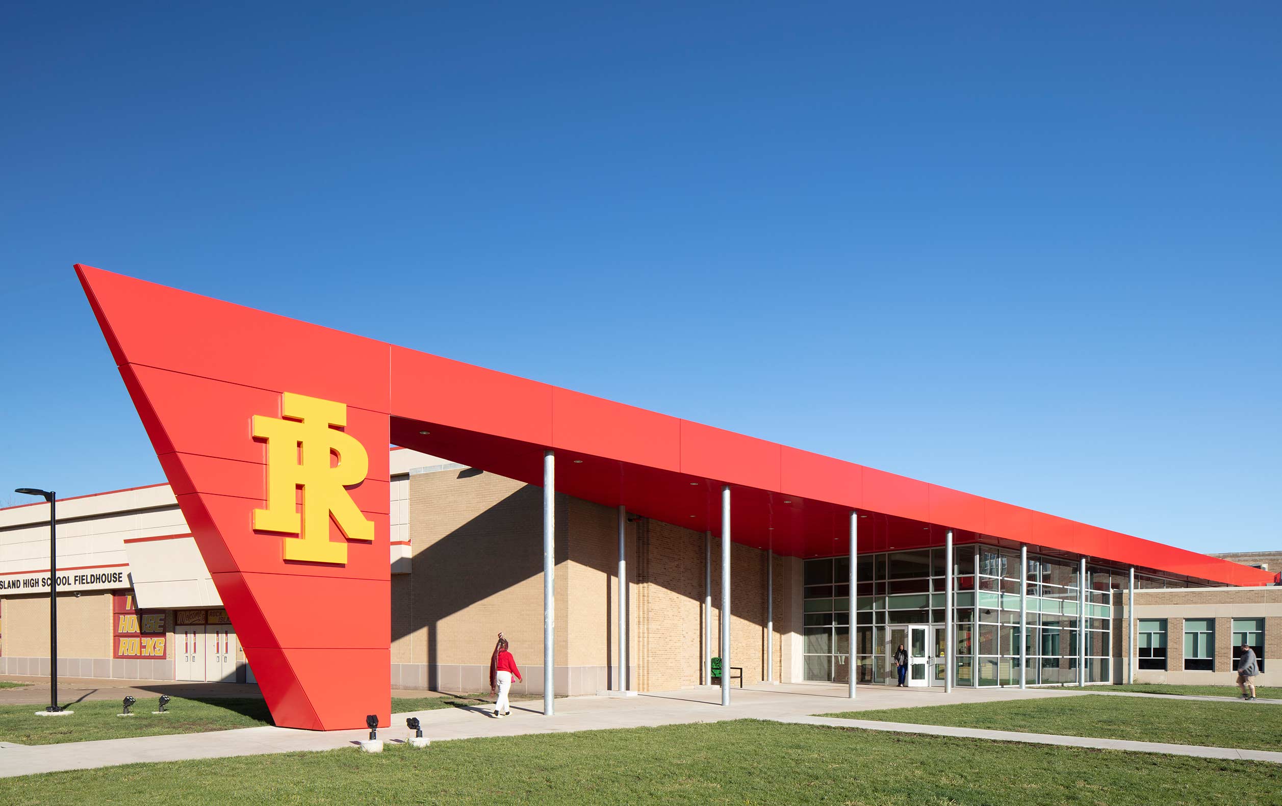 Students entering school beneath bright red, pointed canopy