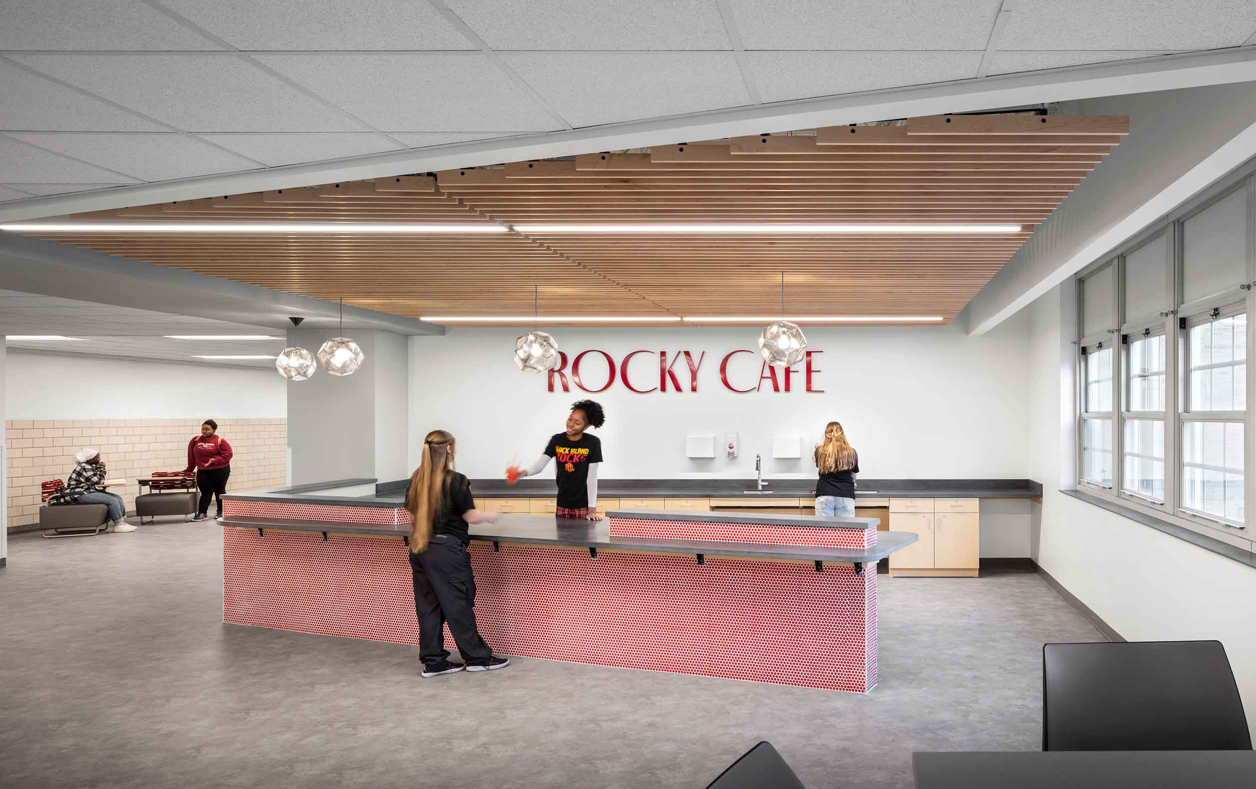 High school students behind counter with Rocky Cafe sign on back wall and wooden ceiling slats