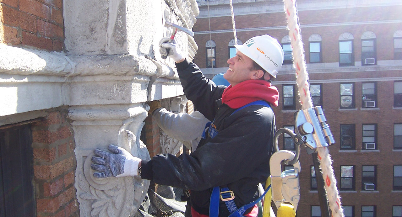 Architect in harness examining wall of masonry building