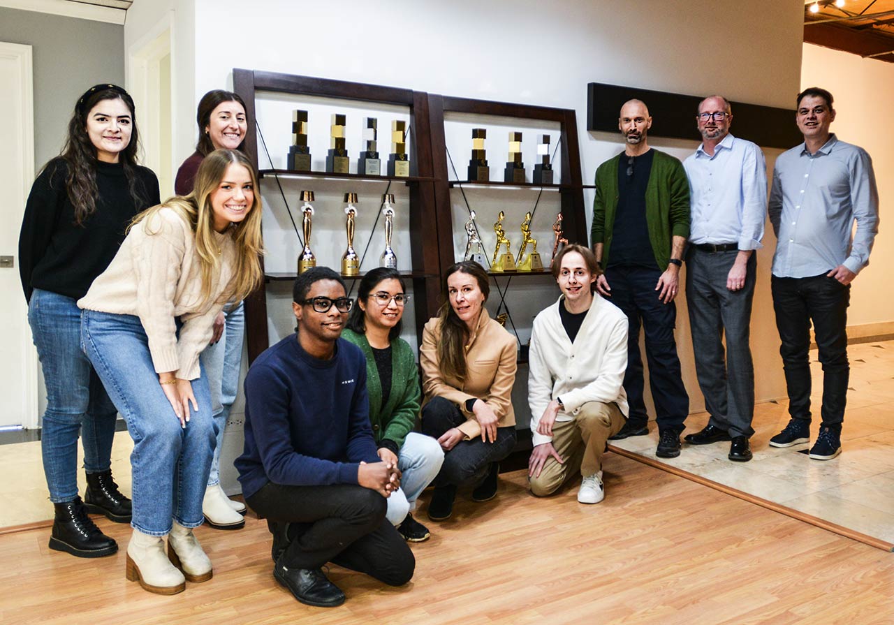 Legat and ArtVersion team members standing before awards display case