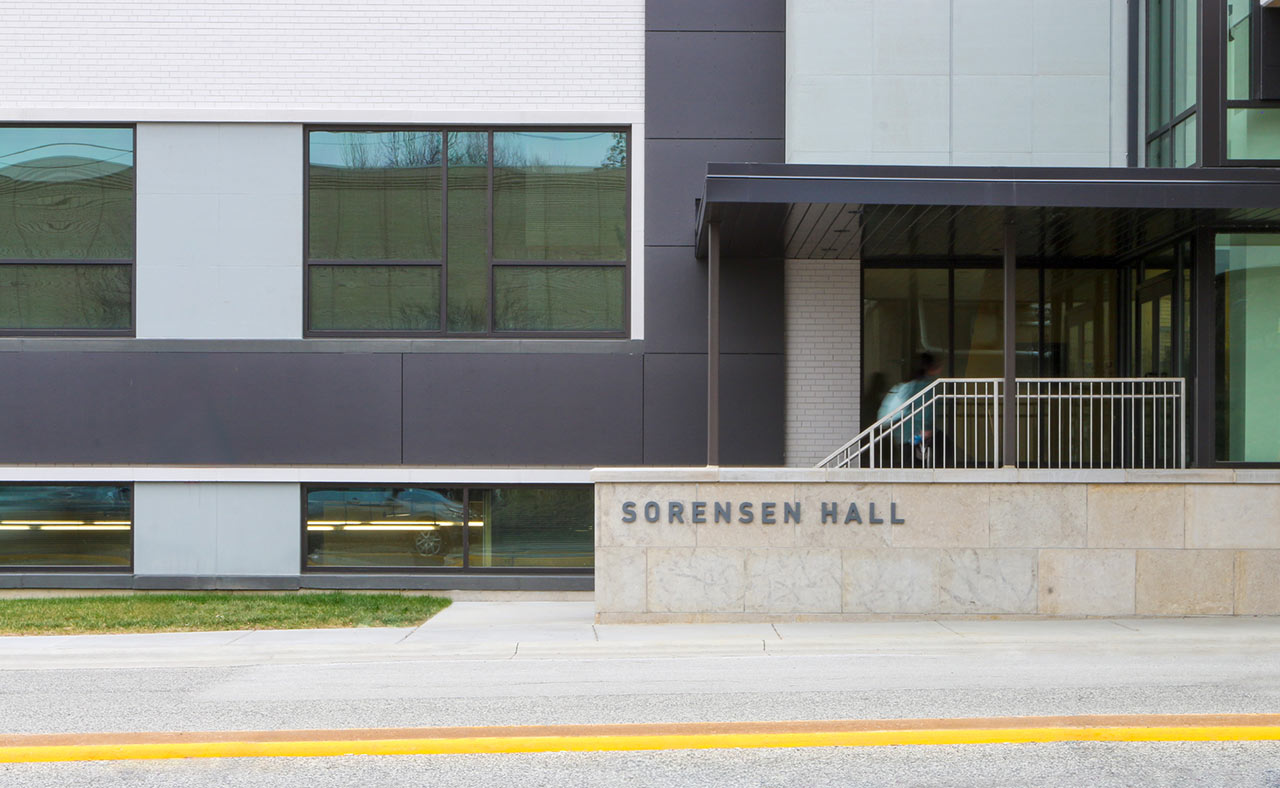 Entry to gray and dark gray building with student walkling up stairs