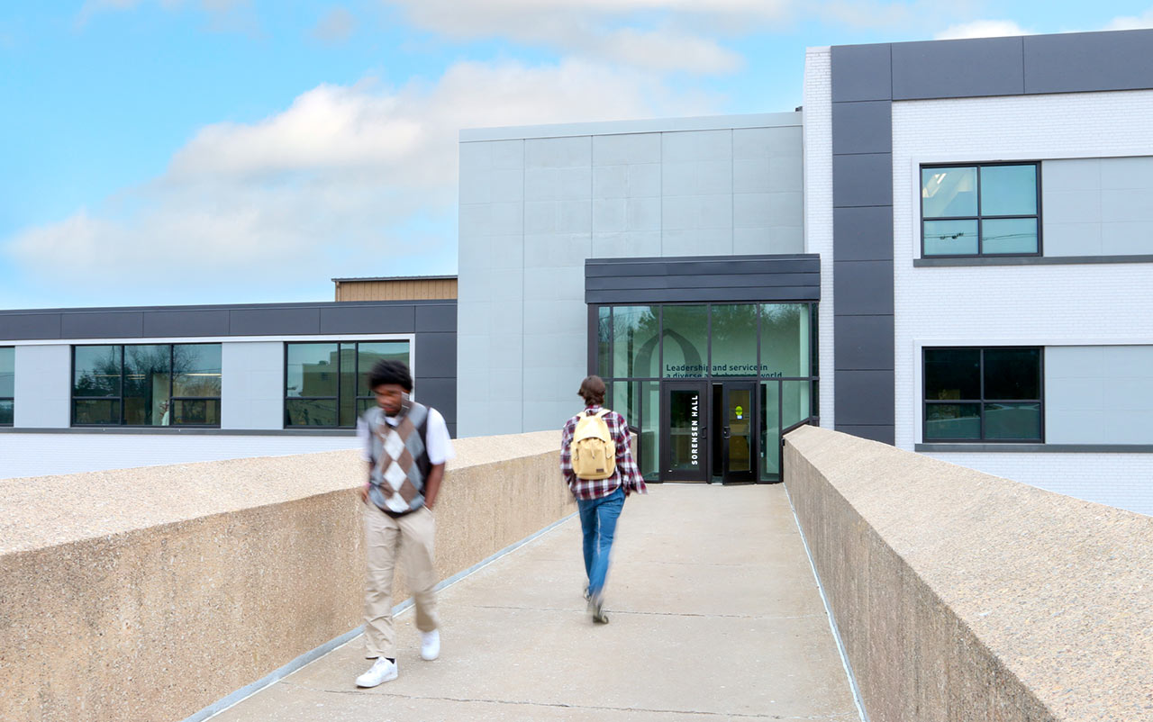 Students on concrete bridge approaching a facility entrance