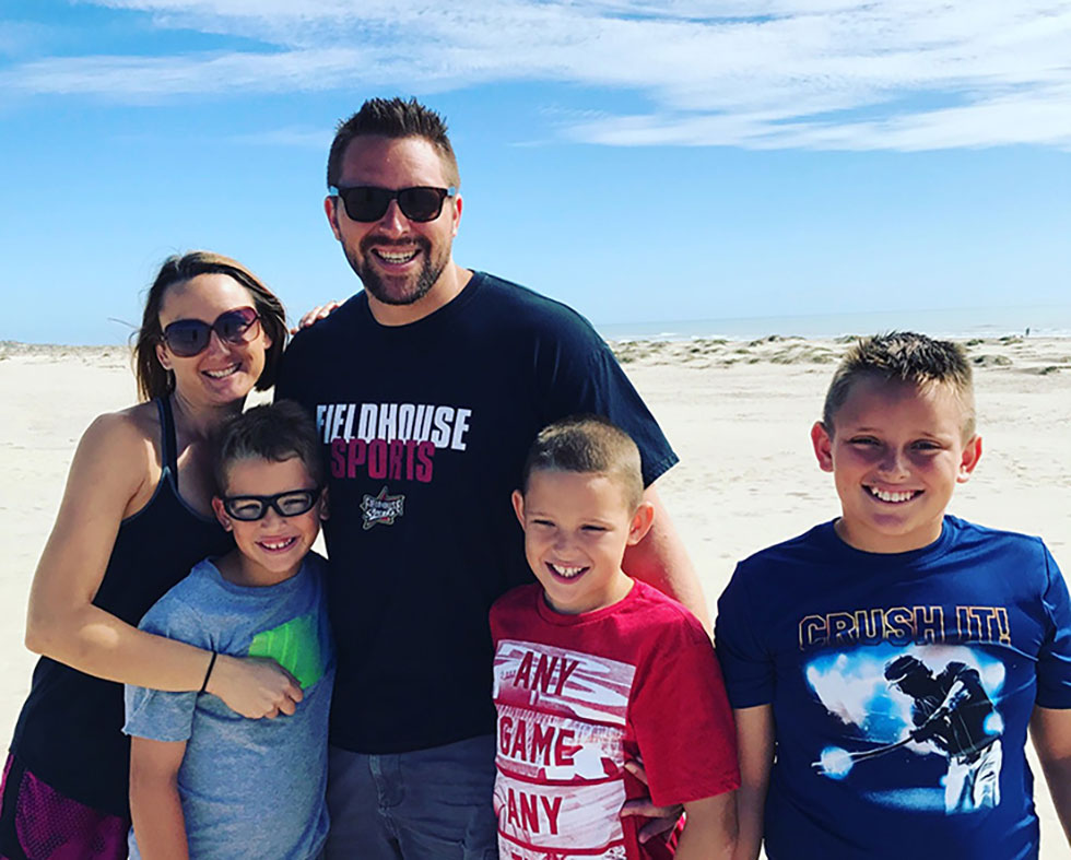 Family including mother, father, and three boys standing on a beach