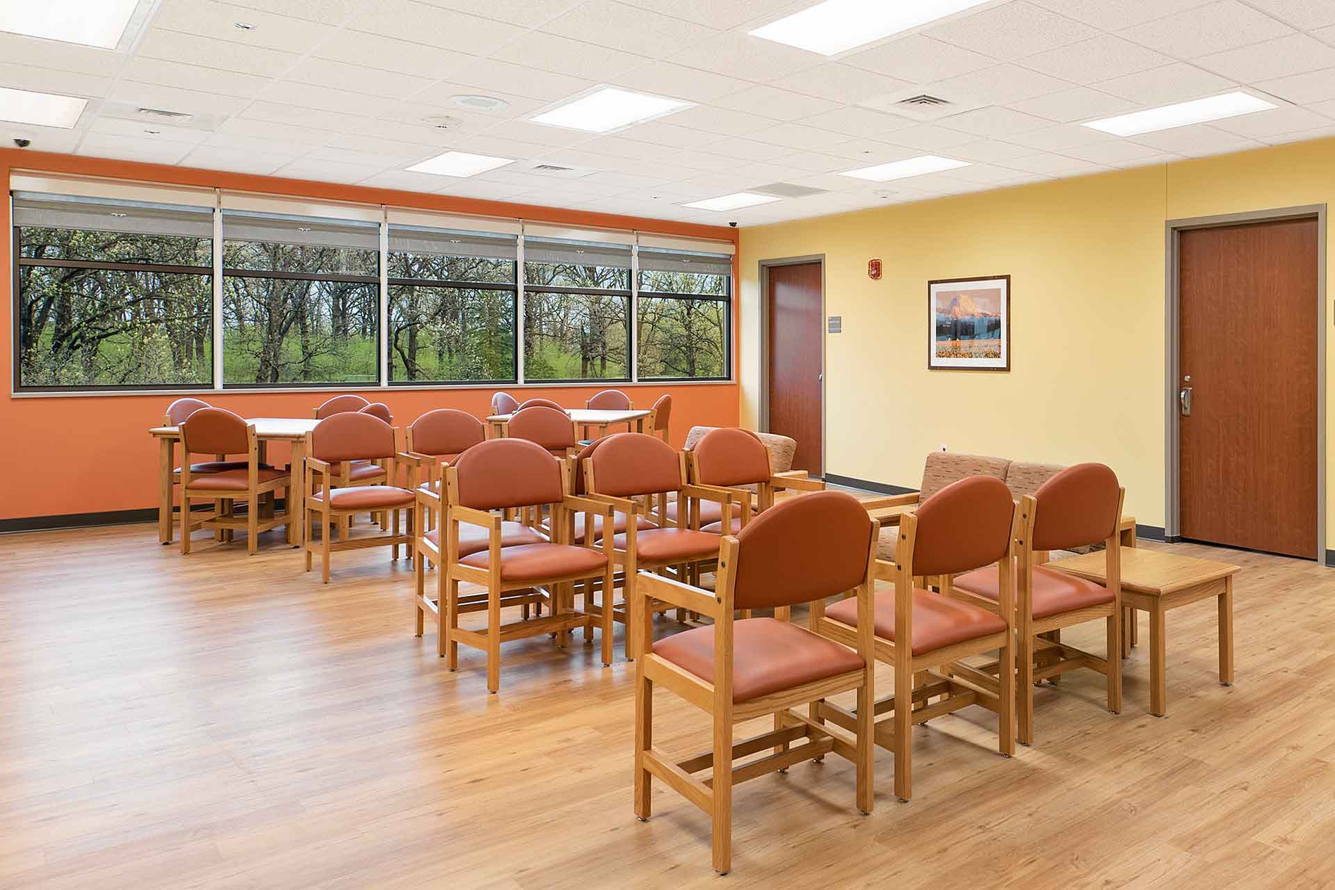 Behavioral hospital day room with windows displaying treetops