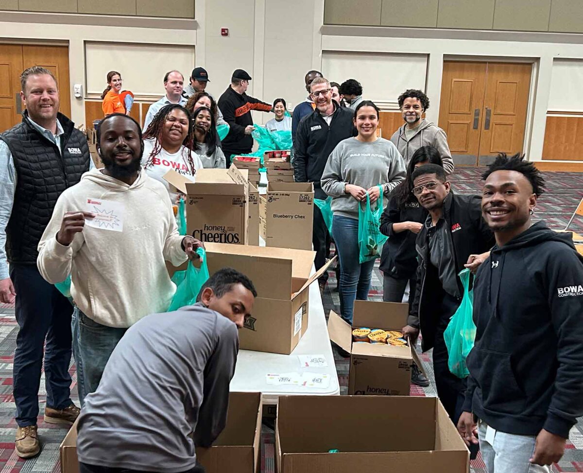 Volunteers smile while packing food items into boxes and bags during a community service event.