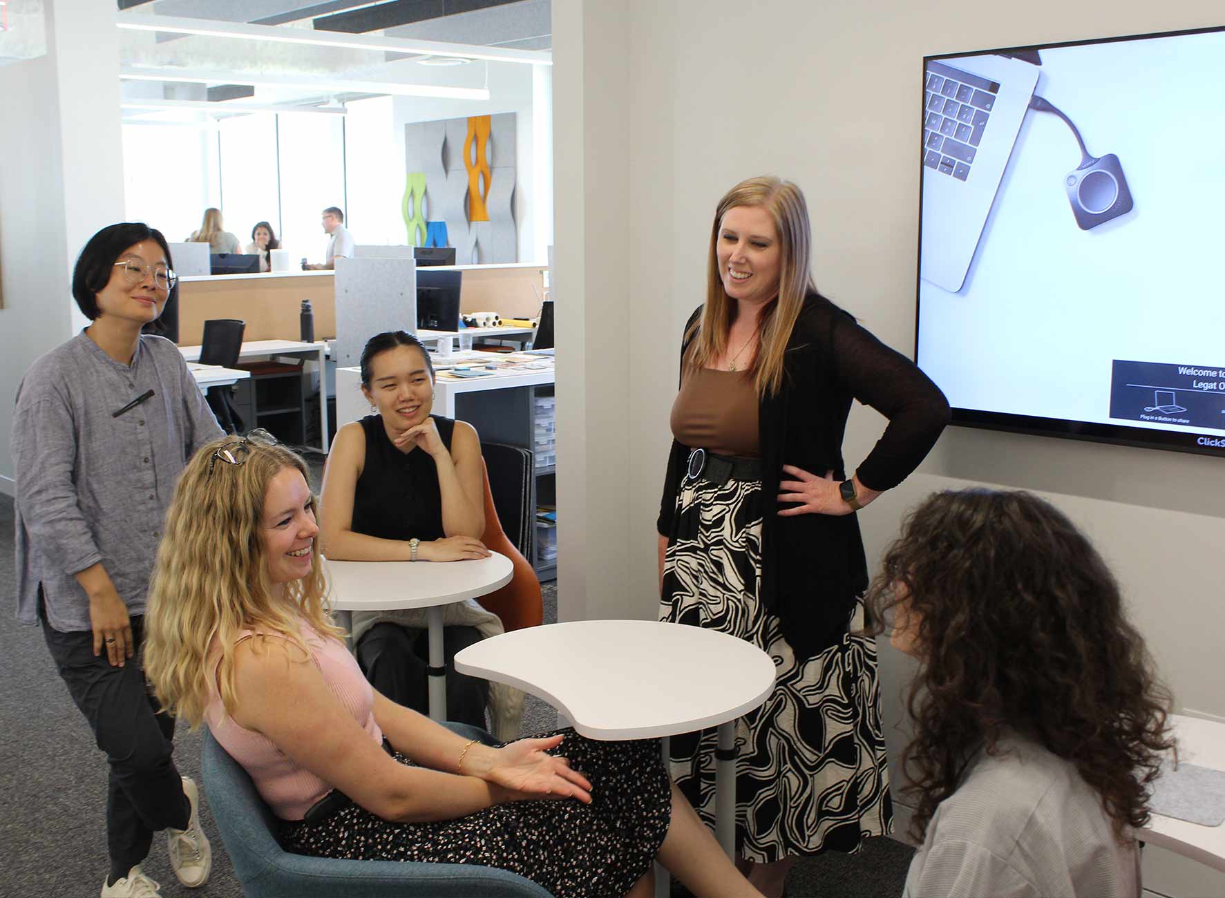 Small group of coworkers smiling and brainstorming together in a modern office space.