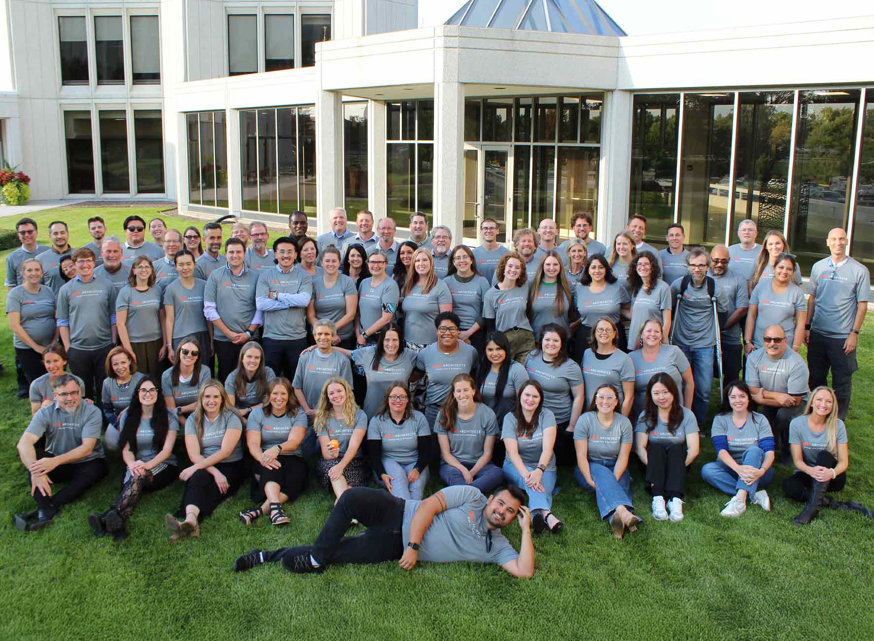 Large group photo of the Legat Architects team wearing matching shirts and smiling together outside the office.