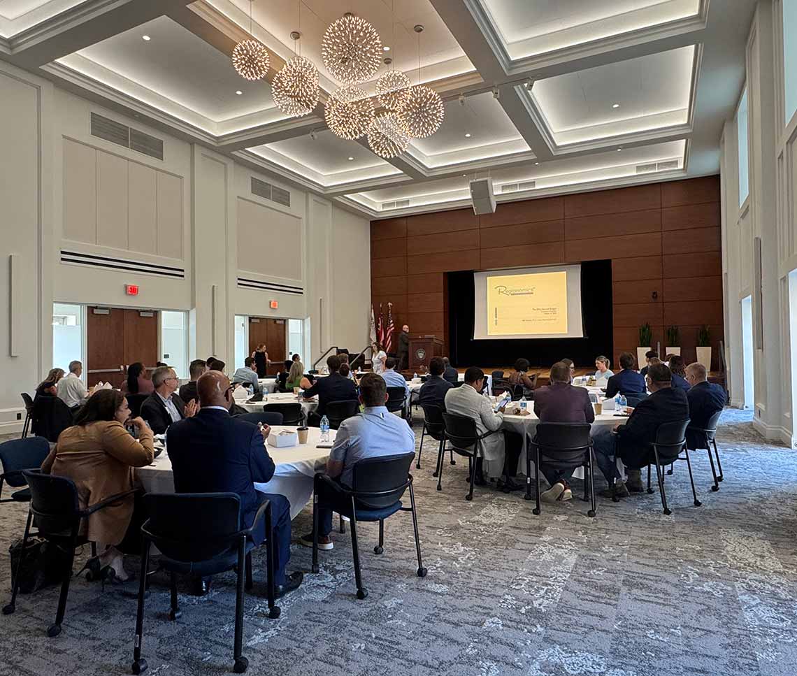 Contemporary college auditorium with dark wood panels around stage and copper ceiling