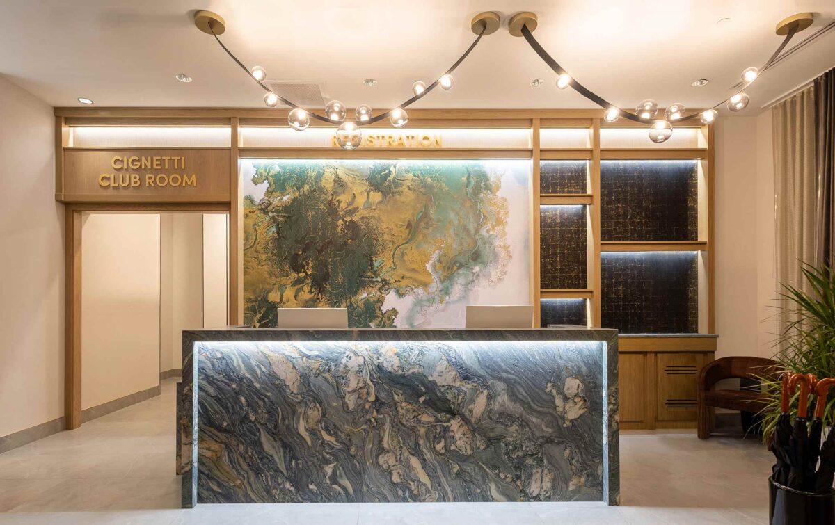 Hotel lobby with green stone reception desk and abstract green and yellow wall covering
