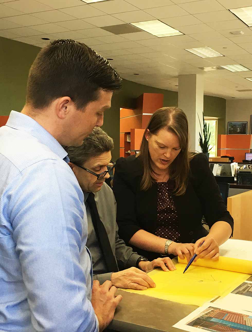 Three architects investigate drawings.