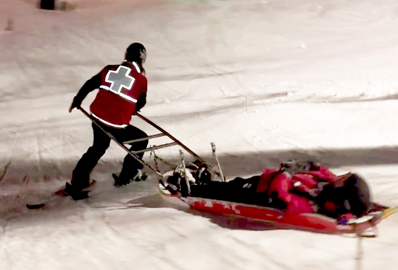 Ski patroller transporting patient in toboggan 