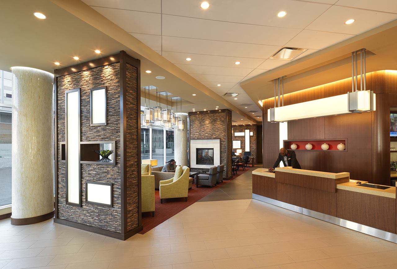Hotel lobby with fireplace, pendant lights, reception desk, view to street