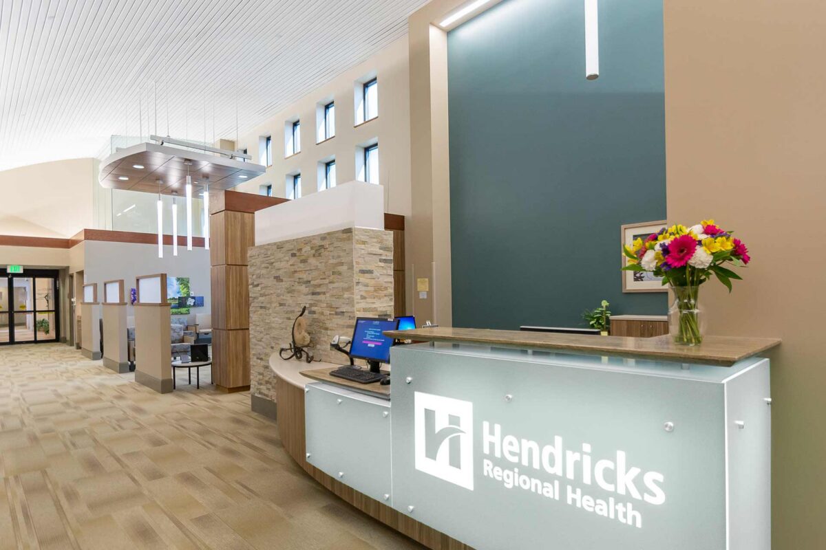 Reception desk in a modern healthcare facility with high ceilings, natural light, and welcoming interior design.