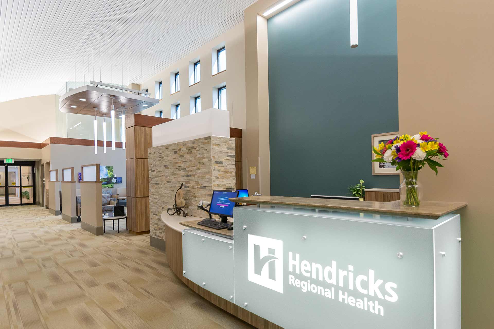 Reception desk in a modern healthcare facility with high ceilings, natural light, and welcoming interior design.