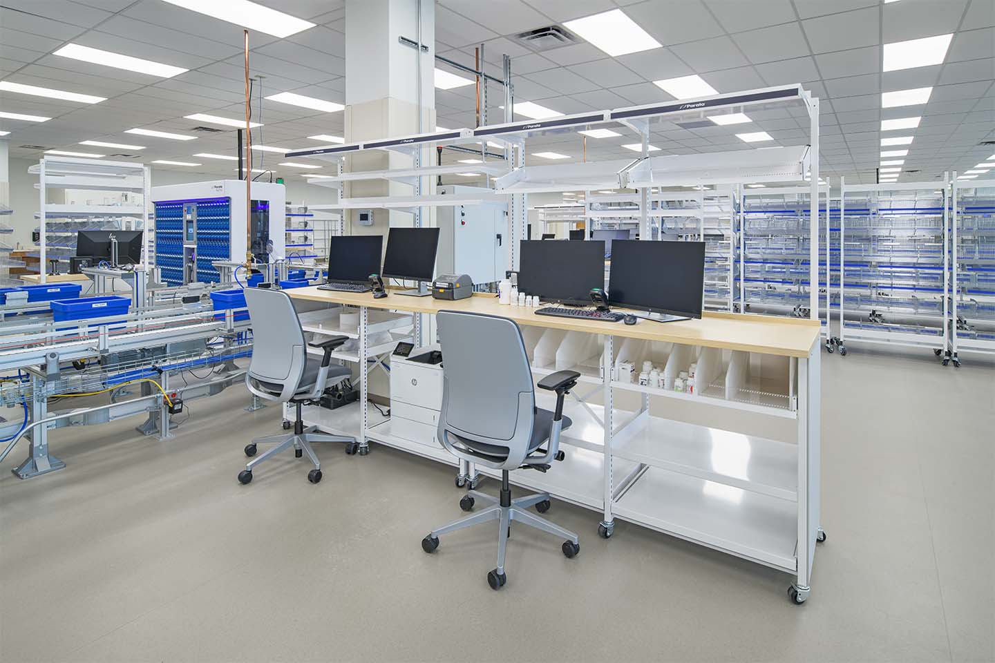 Modern automated laboratory with conveyor systems, workstations, and storage racks in a clean production facility.
