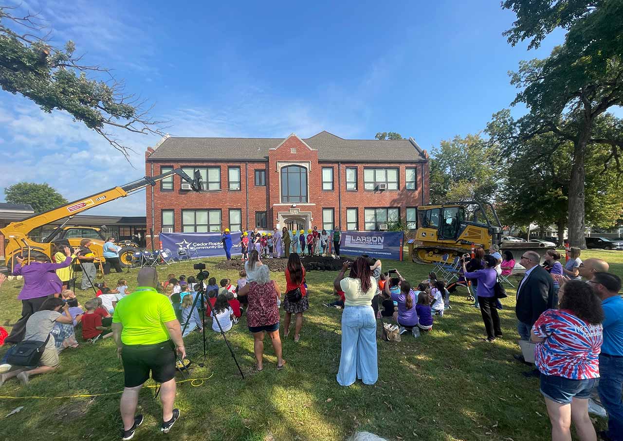 Groundbreaking ceremony for the renovation and expansion of historic Harrison Elementary School in Cedar Rapids, Iowa, with students, staff, and community members gathered outside the school.