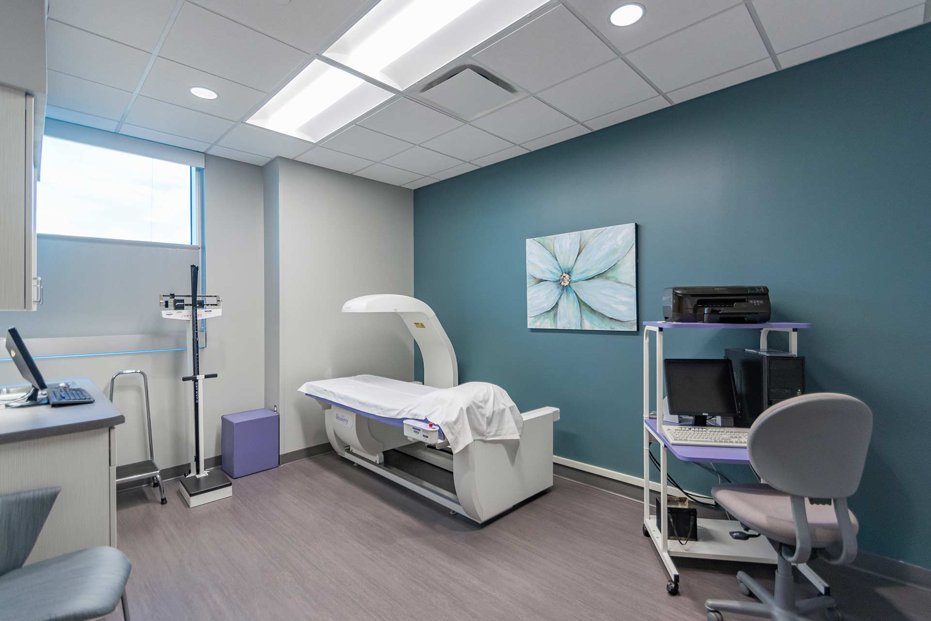 Bone density scan room with imaging equipment, computer workstation, and patient exam table.