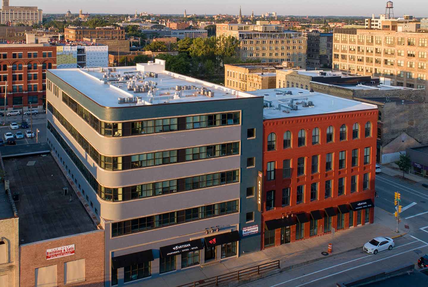 Aerial view of Artisan building in urban city setting with red brick and grey exteriors.